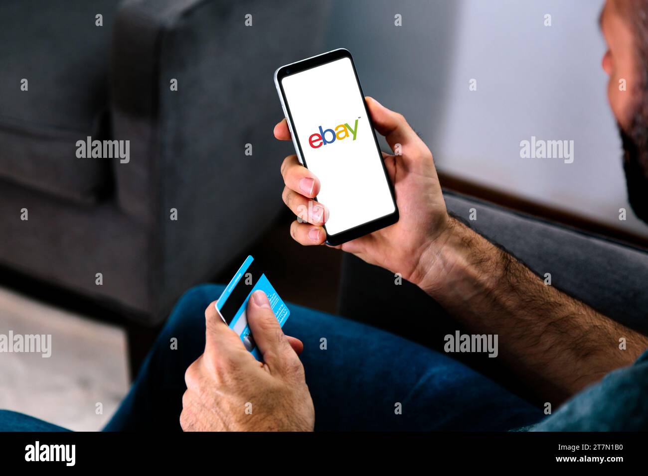 Logo eBay sullo schermo del telefono tenuto da un uomo con una carta di credito all'altra mano. ROSARIO, ARGENTINA - 15 NOVEMBRE 2023. Foto Stock