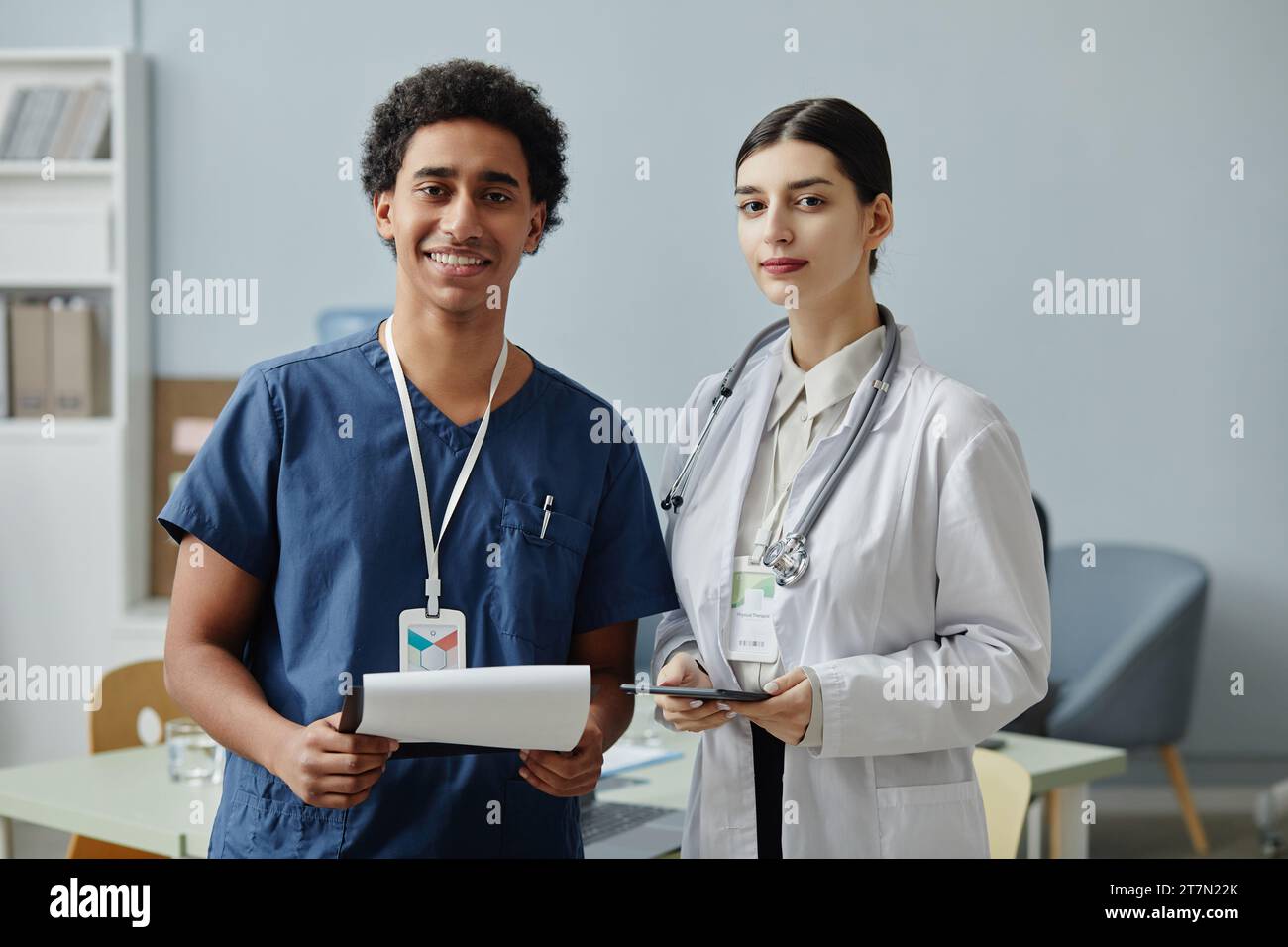 Vita in alto ritratto di due giovani stagisti medici che guardano la macchina fotografica in piedi nell'ufficio della clinica, spazio copia Foto Stock