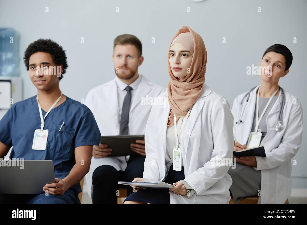 Gruppo eterogeneo di medici seduti in platea a seminari educativi e ascoltando lezioni di medicina Foto Stock