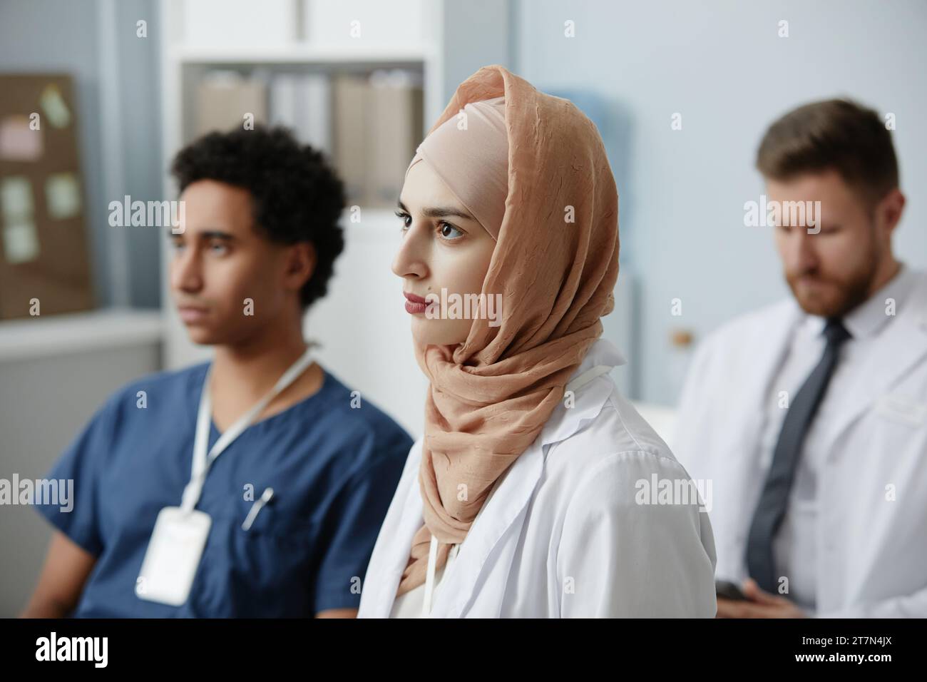 Vista laterale ritratto di una giovane donna musulmana come medico nel seminario di formazione ascoltando la lezione in pubblico Foto Stock