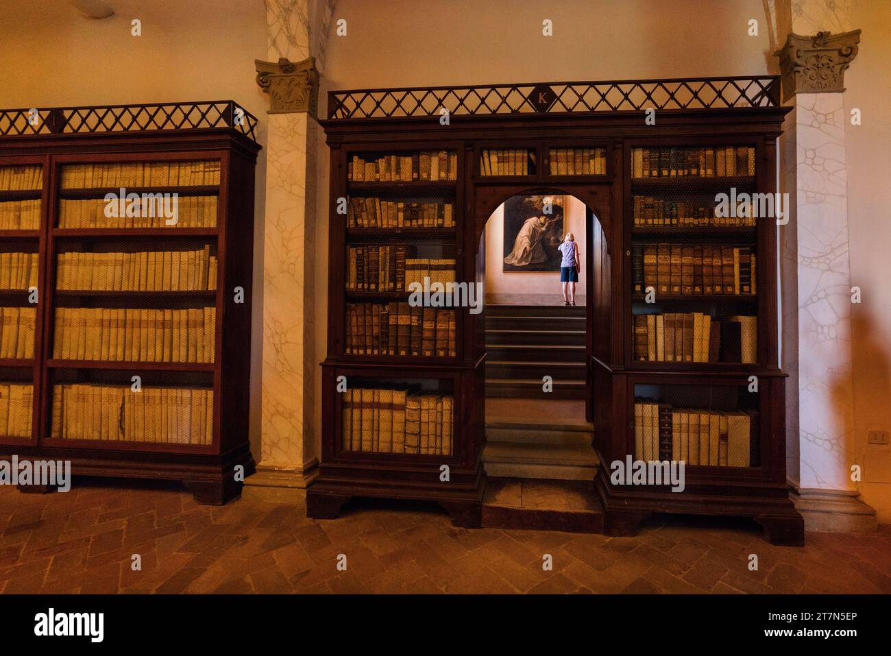 Asciano, Italia: Un turista sale una scalinata al centro di librerie nella biblioteca, il suggestivo Monastero di Oliveto, Monte Oliveto Foto Stock