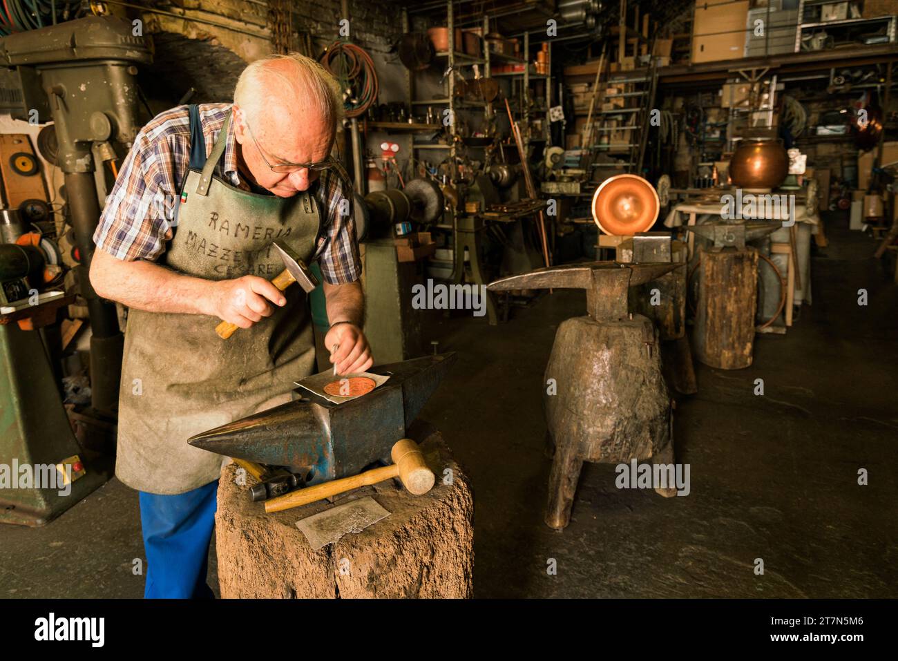 Montipulicano, Italia: Cesare, un rinomato artigiano locale sta martellando un disegno in un pezzo di rame nella sua bottega dove h Foto Stock