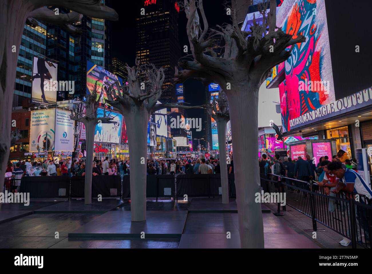 Persone che camminano di notte a Times Square, con vivaci pannelli a LED, grattacieli torreggianti, negozi e il vivace paesaggio urbano di Broadway Foto Stock