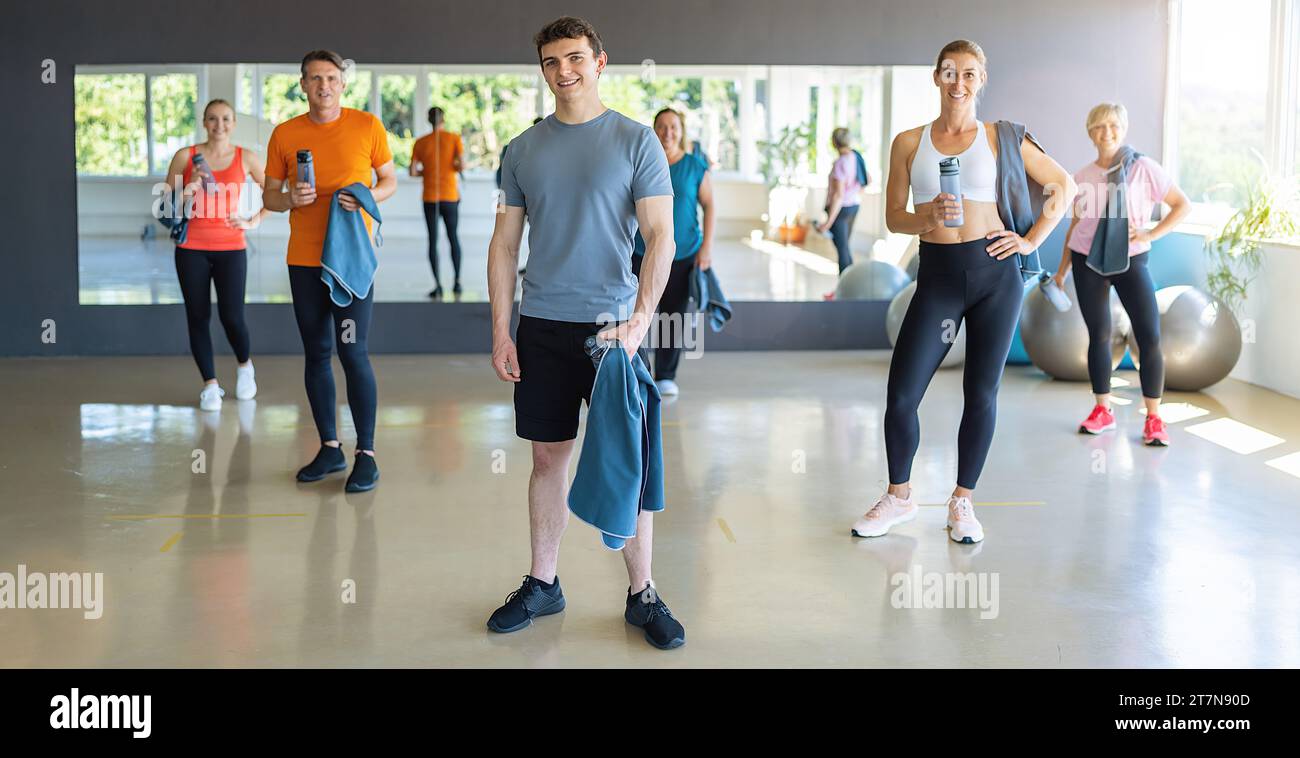 Gruppo di persone con attrezzature da palestra sorridenti e in piedi in un centro fitness. Immagine del concetto di lavoro di squadra Foto Stock