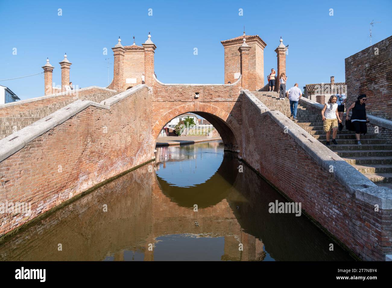 Comacchio, Italia-2 giugno 2023: Le persone passeggiano a Comacchio davanti ai famosi tre ponti durante una giornata di sole Foto Stock