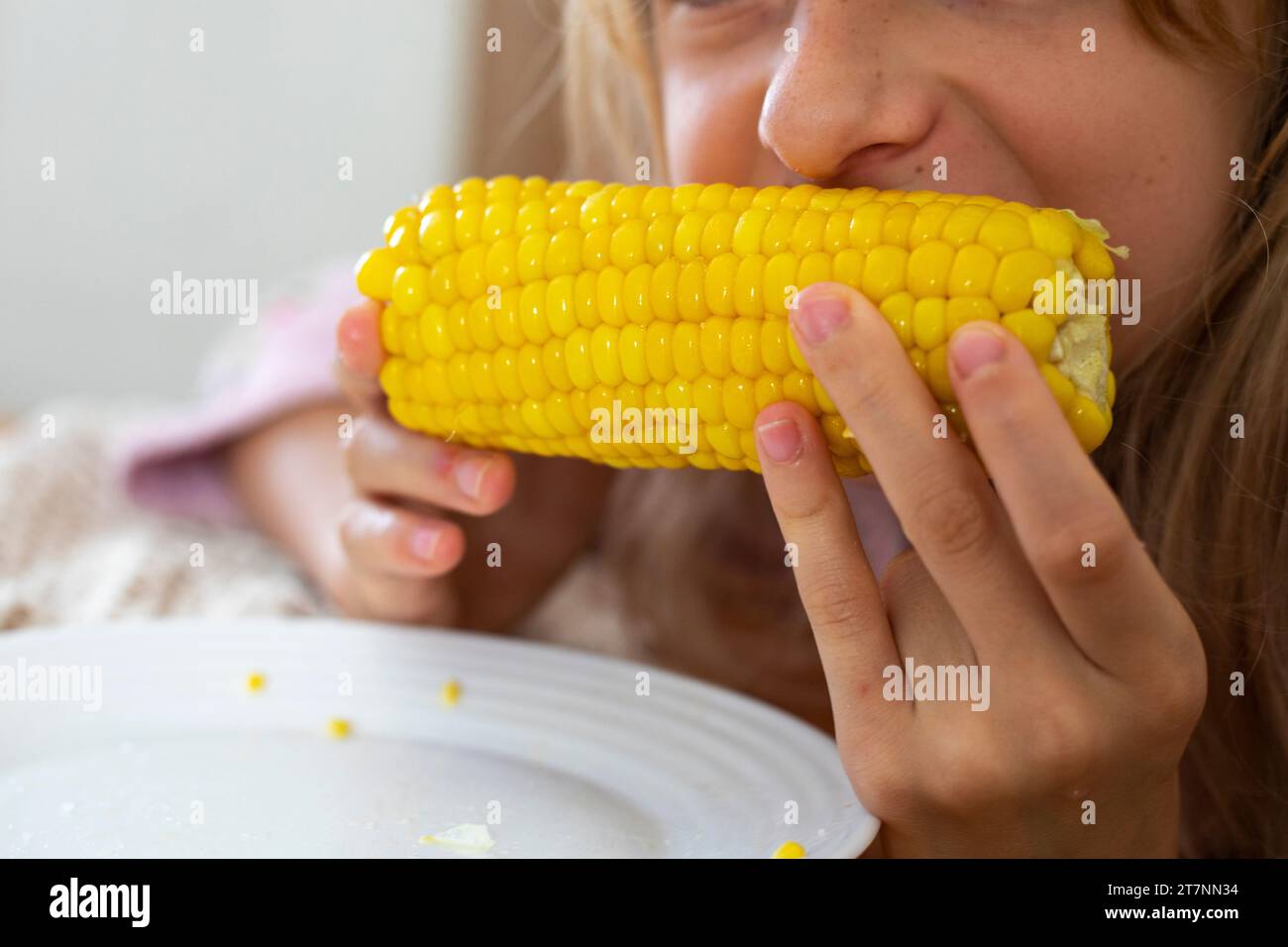 mangia mais dolce giallo caldo con sale e burro tenendolo con entrambe le mani Foto Stock