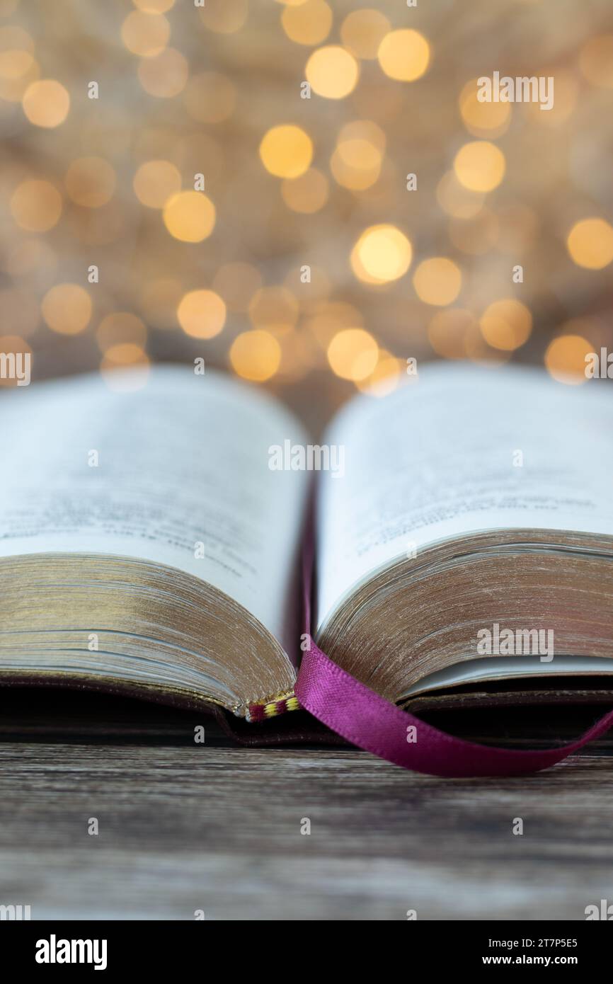 Libro Sacro della bibbia aperto su un tavolo di legno con sfondo bokeh dorato. Primo piano. Shot verticale. Messa a fuoco selettiva. Studiare il concetto delle Scritture cristiane. Foto Stock