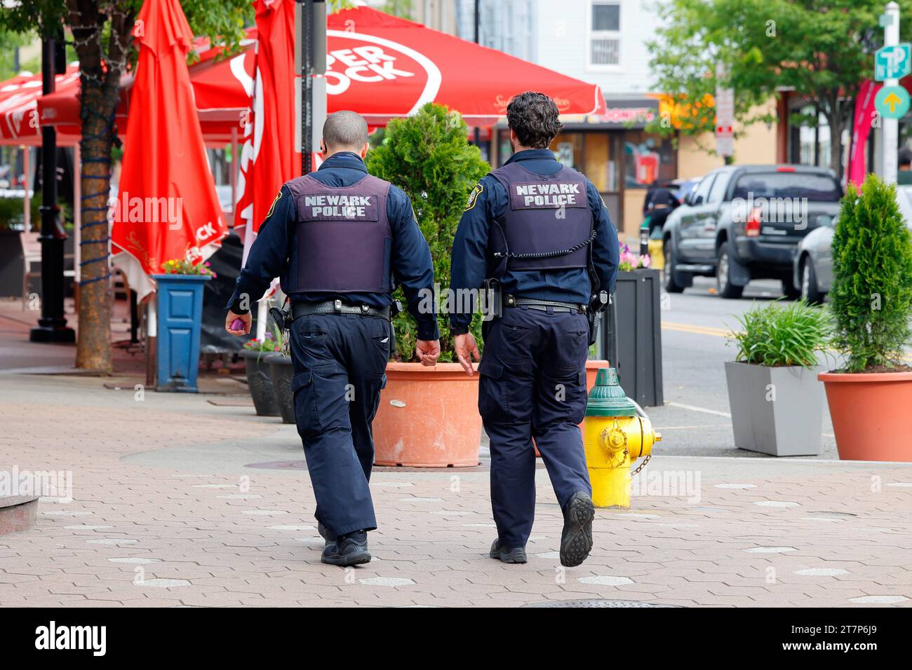Due poliziotti di Newark che camminano lungo una strada nel quartiere di Ironbound, Newark, New Jersey. Foto Stock