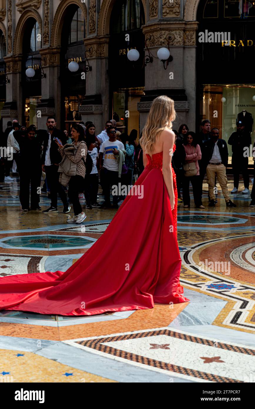 Modella di moda con un abito rosso brillante in un servizio fotografico presso il centro commerciale Galleria Vittorio Emanuele Foto Stock