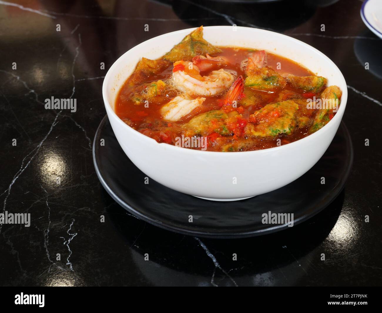 Uovo fritto con foglie di cha om o omelette di acacia e gamberi freschi in una zuppa di curry acida in una ciotola bianca, cucina asiatica tradizionale in Thailandia Foto Stock