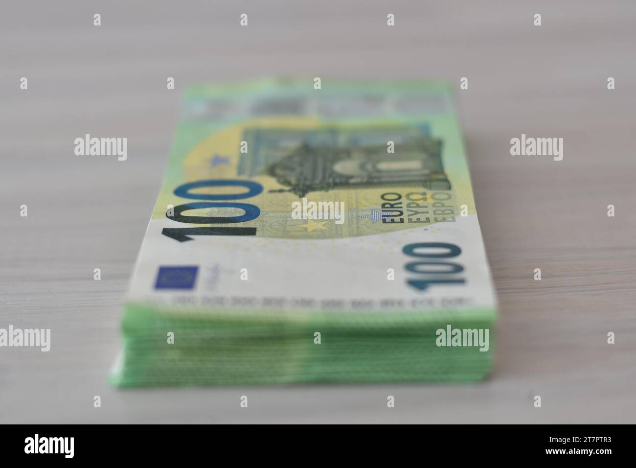 Molte banconote da cento euro in pila su un tavolo, che simboleggiano denaro contante, ricchezza o corruzione Foto Stock