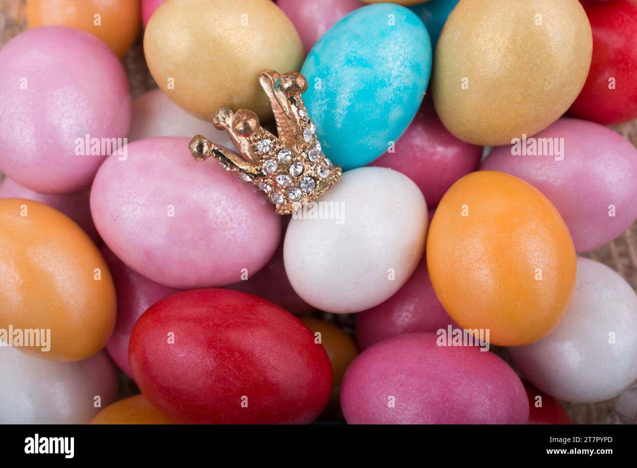 Modello piccolo corona disposta sulla colorata candy uova Foto Stock