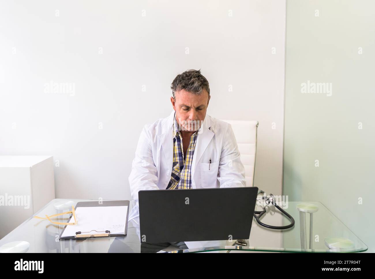 Medico maschile che lavora su un computer portatile in ufficio medico Foto Stock