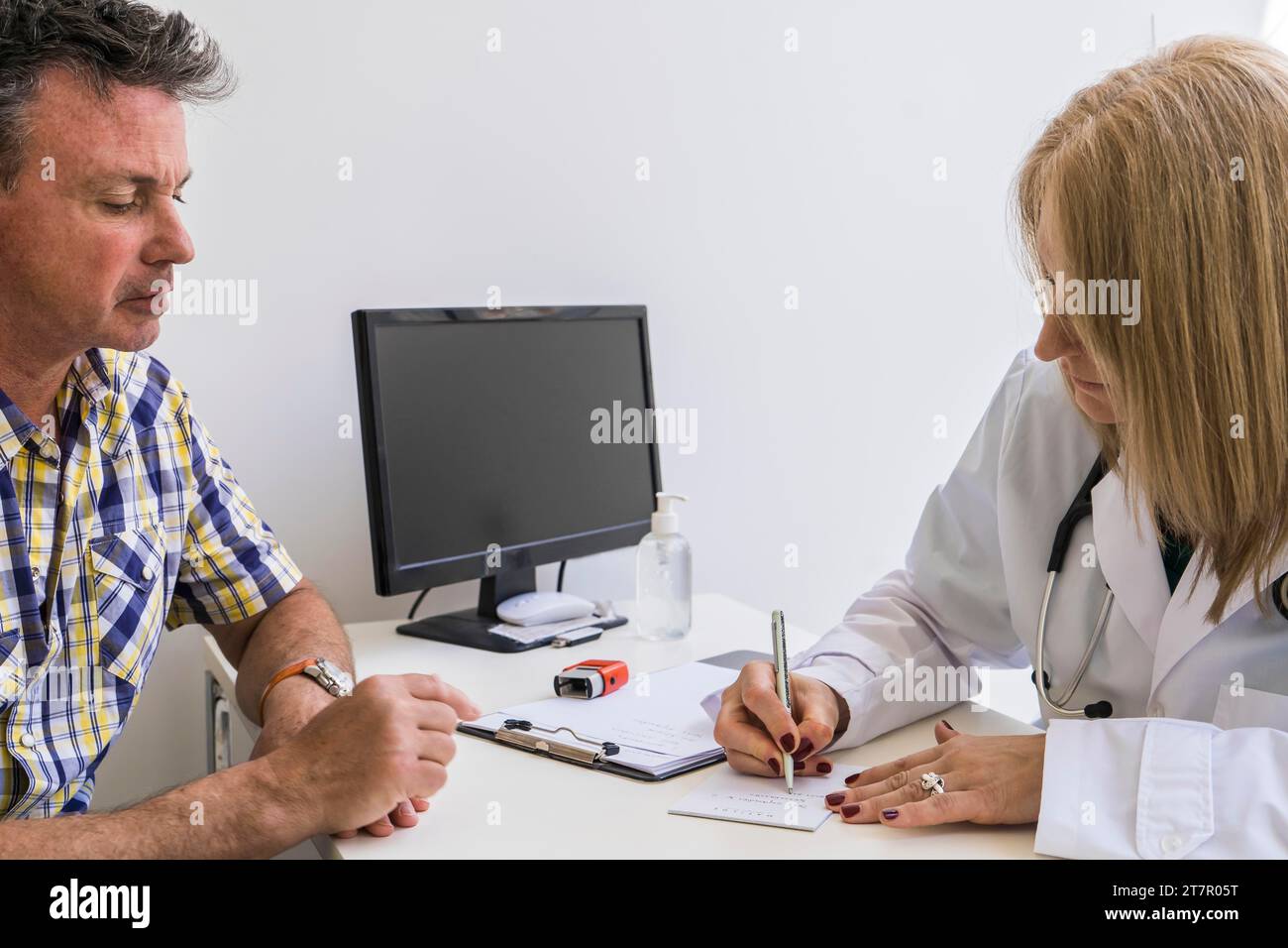 Medico donna che scrive prescrizione al suo paziente Foto Stock