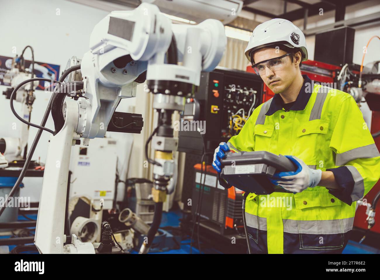 Uomo ingegnere moderno intelligente che utilizza la moderna tecnologia robotica. Configurazione del braccio di saldatura robotizzato nel processo di produzione dell'automazione in fabbrica Foto Stock