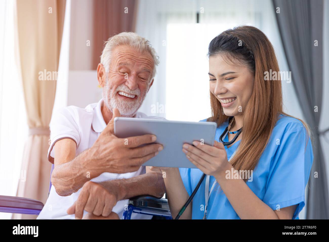 felice sano anziano uomo anziano godere di guardare video chat sullo schermo di tablet in assistenza domiciliare infermieristica con il medico Foto Stock
