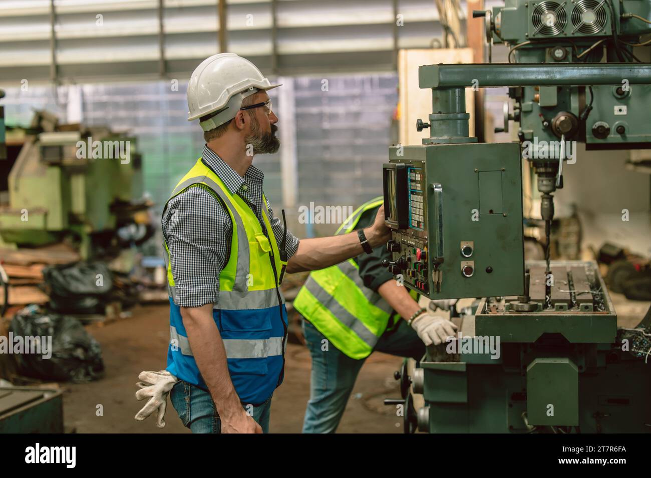 L'ingegnere ispanico senior, il lavoratore esperto, lavora con la fresatrice per tornio di metalli in una fabbrica industriale pesante Foto Stock