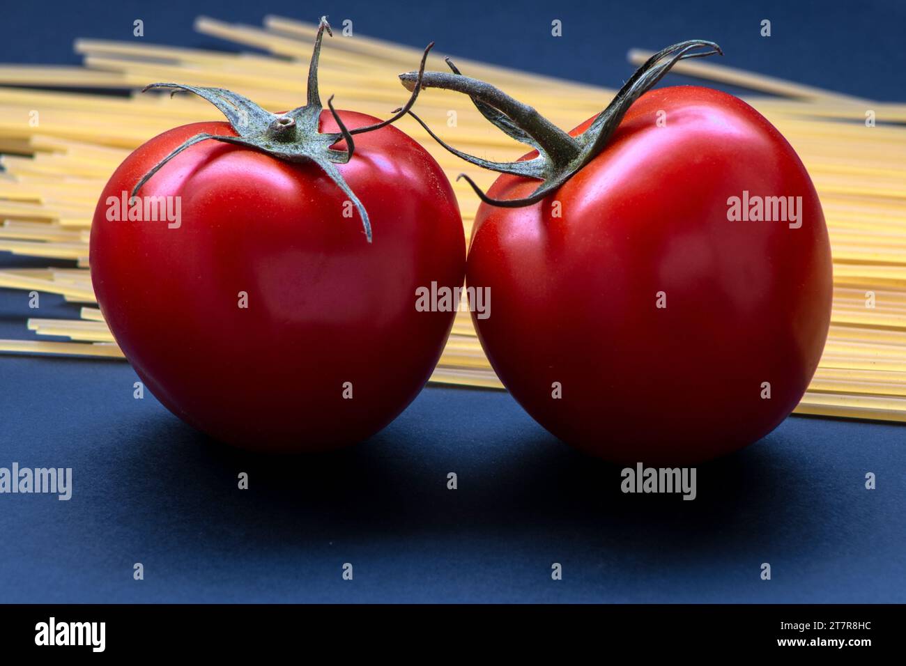 Pomodori e pasta cruda dall'aspetto realistico isolati su sfondo blu in Brasile Foto Stock