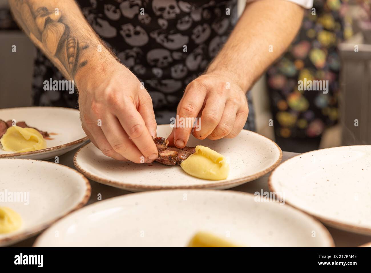 Lo chef organizza pezzi di carne con precisione Foto Stock