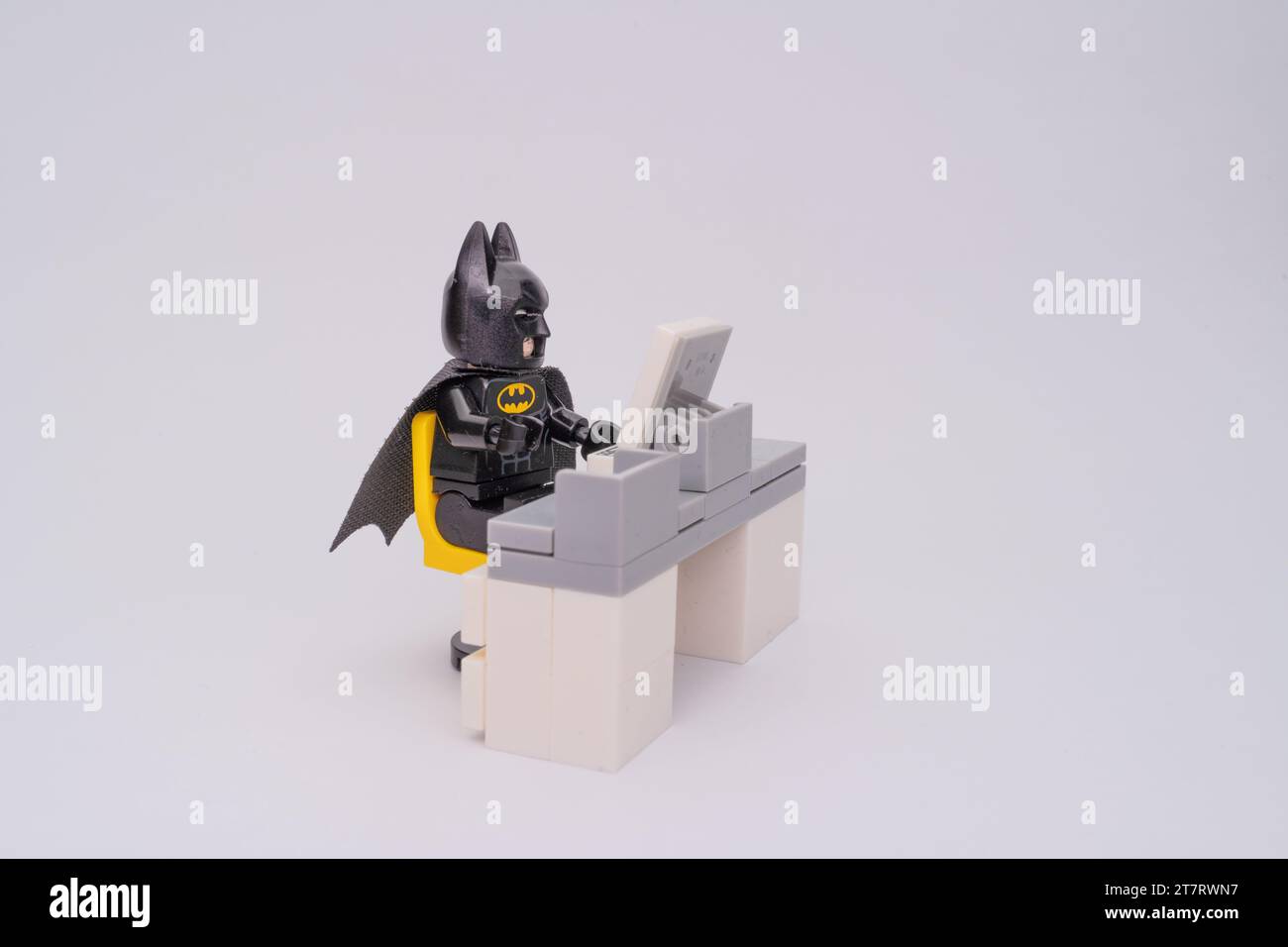 Una statuetta Lego di Batman seduta su una scrivania del computer fatta di pezzi Lego su uno sfondo bianco. Foto Stock