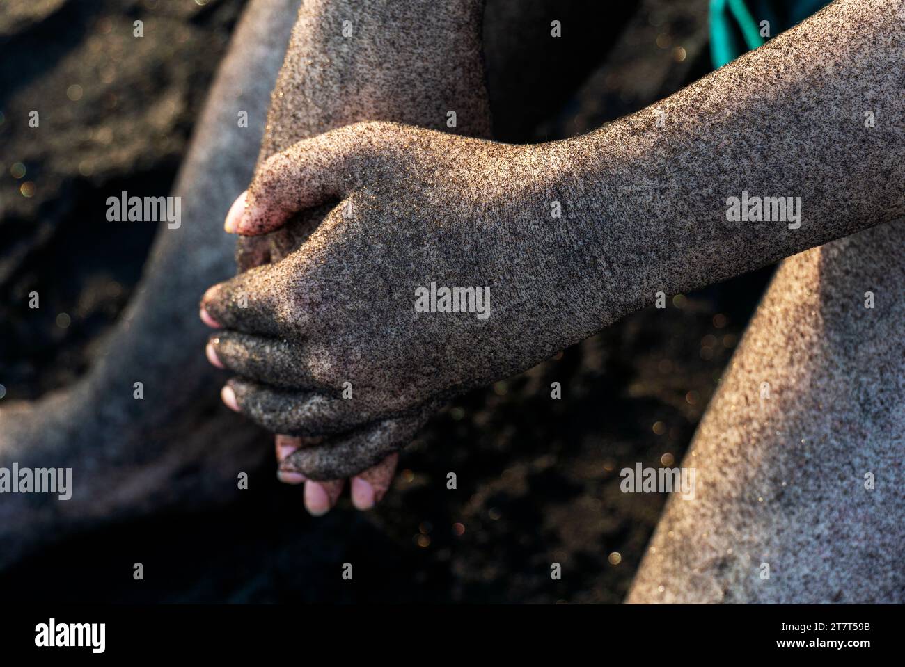 Mani ricoperte di sabbia nera Foto Stock