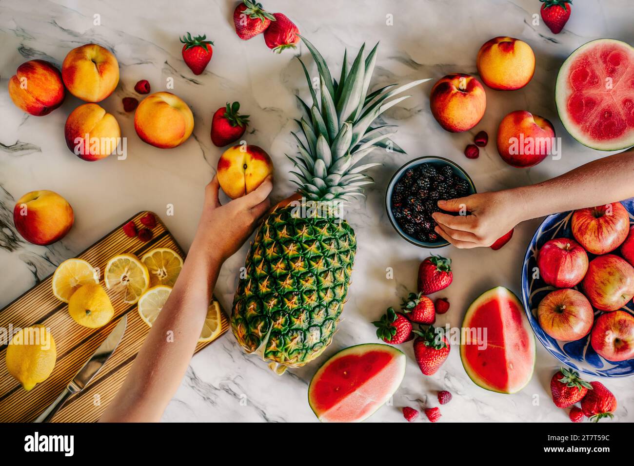 Disposizione della frutta con le mani che raggiungono Foto Stock