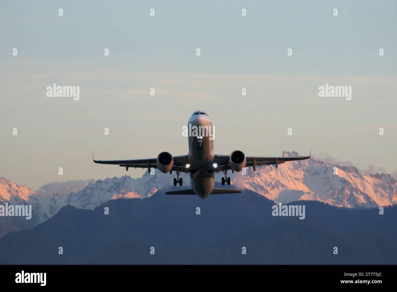 Aereo nel cielo blu e montagne sullo sfondo al tramonto Foto Stock