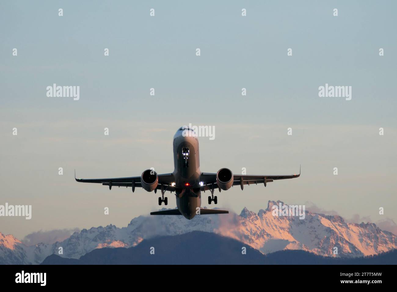 Aereo nel cielo blu e montagne sullo sfondo al tramonto Foto Stock