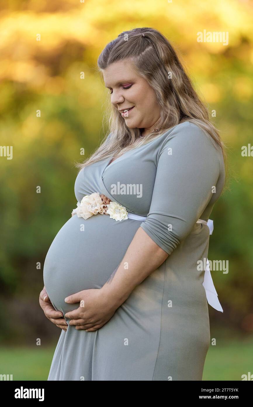 Foto di maternità di una donna che guarda in basso e che afferra la sua pancia Foto Stock