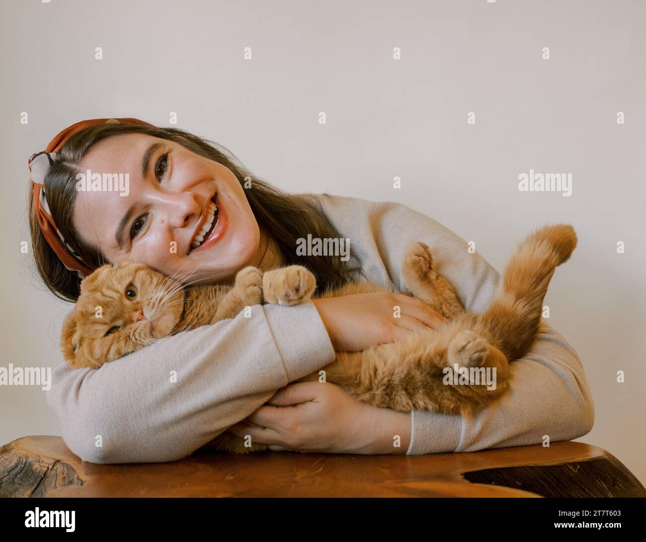 Giovane donna felice con un gatto scozzese arancione, entrambi sorridenti Foto Stock