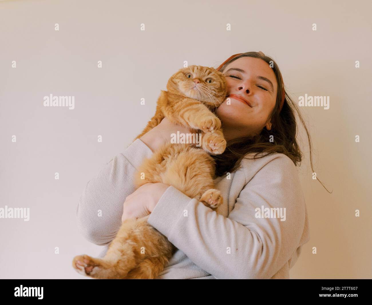 Una giovane donna tiene il suo gatto Scottish Fold in un abbraccio. Foto Stock