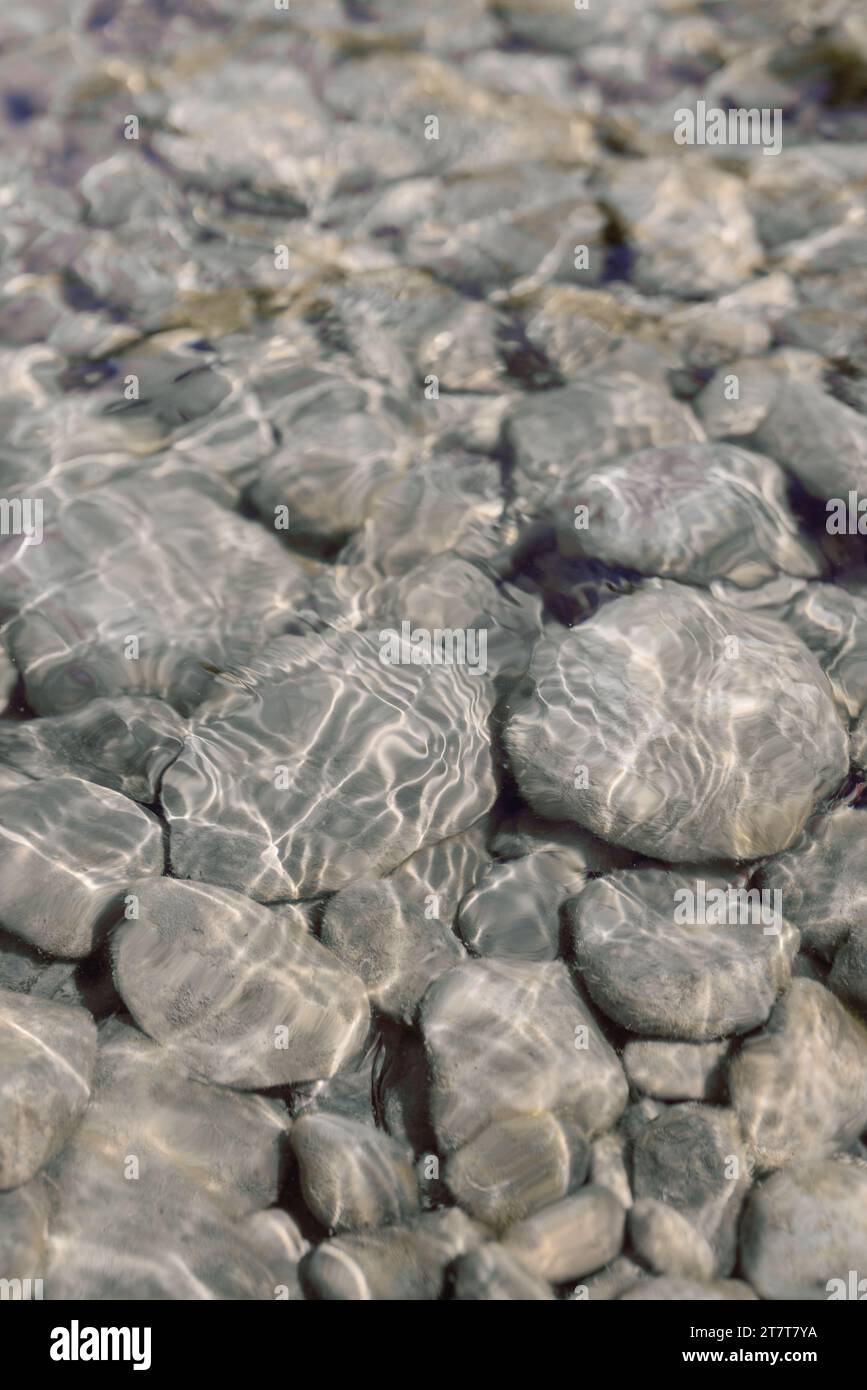 Rocce che brillano al sole di un fiume tranquillo e cristallino Foto Stock