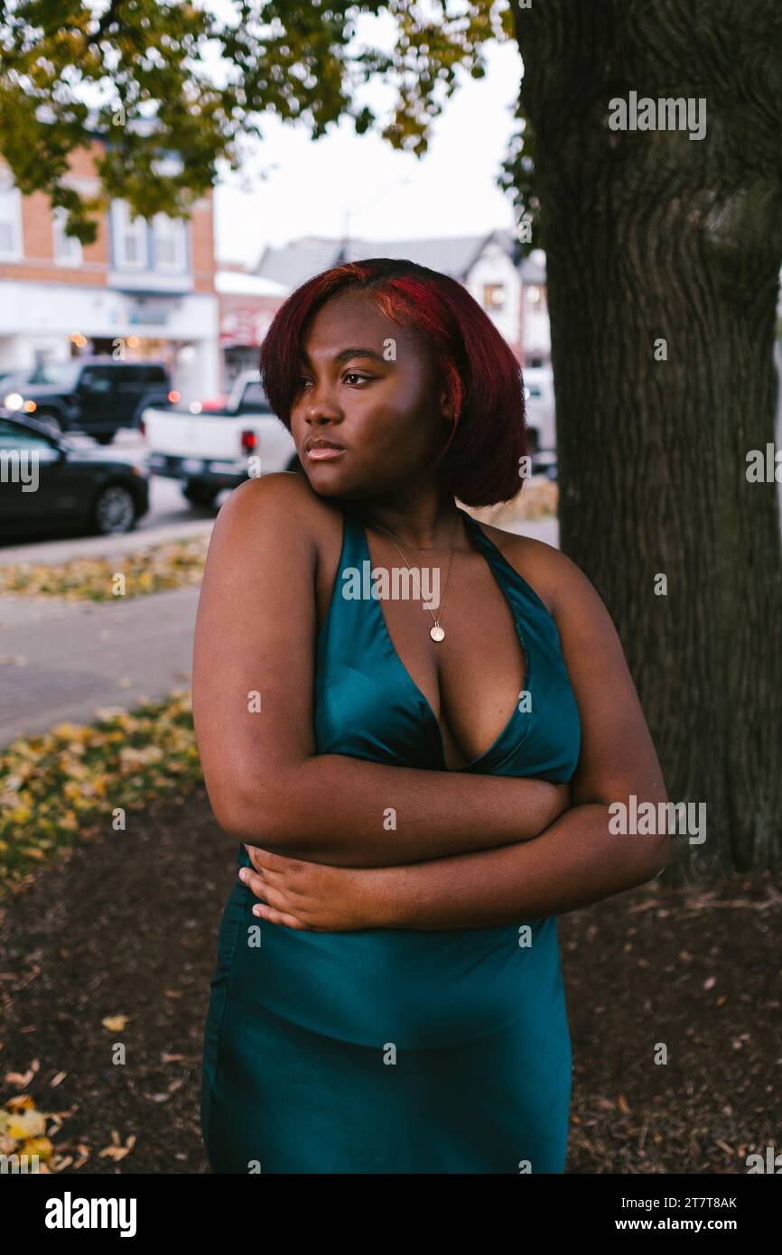 Modello nero femminile in abito verde in centro città Foto Stock