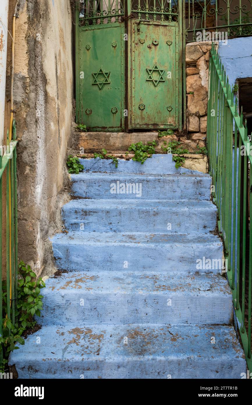 Una scala blu chiaro conduce ad un cancello con porte verdi e stelle ebraiche in un vicolo della città israeliana di Safed. Foto Stock