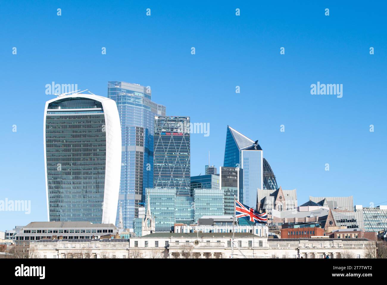 Grattacieli ed edifici della città di Londra visti dietro la bandiera di Union Jack Regno Unito in una luminosa giornata di sole con un cielo blu Foto Stock