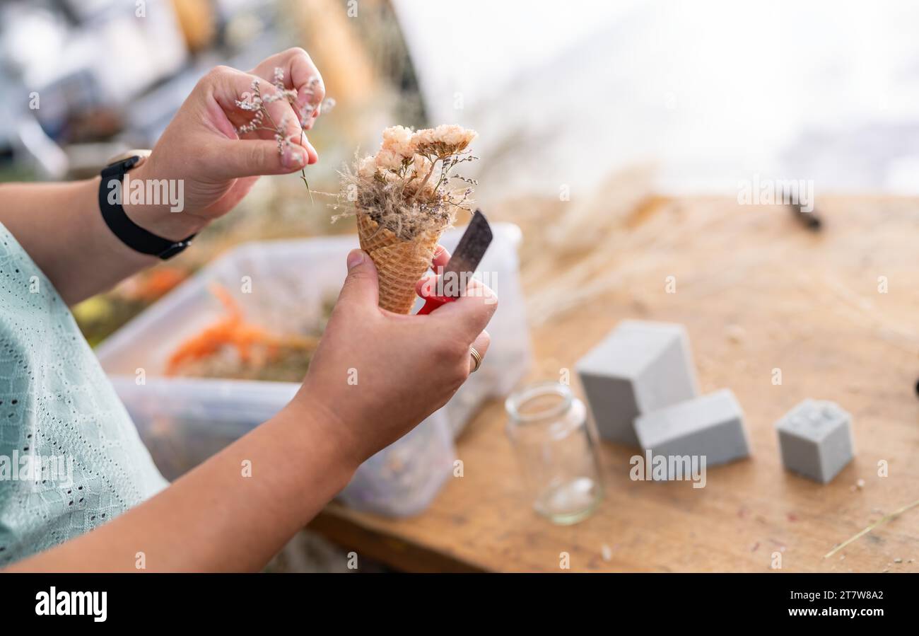 Fiorista che crea un bouquet con fiori secchi in un cono gelato Foto Stock
