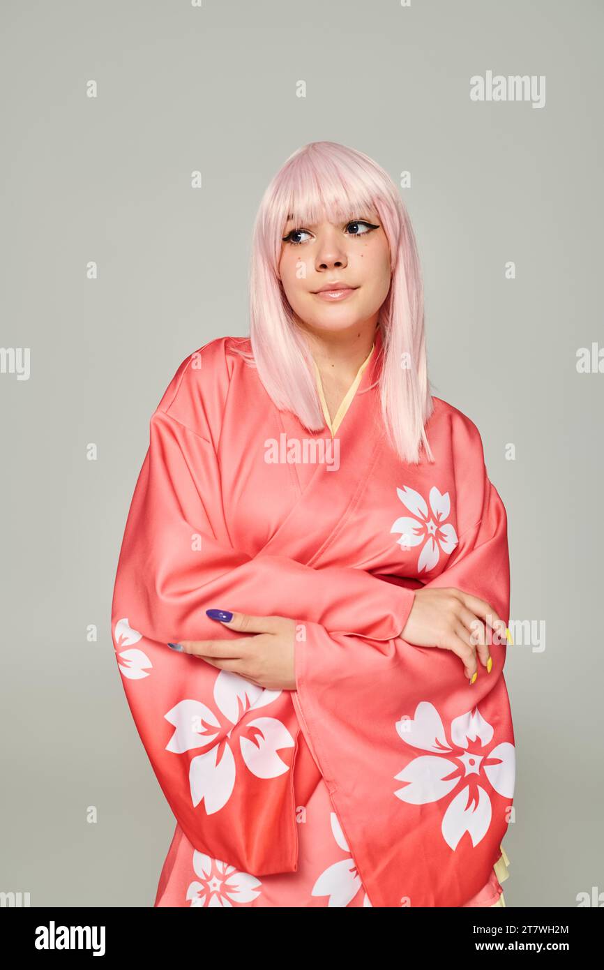 donna bionda con manicure colorate in kimono rosa con stampa floreale in stile grigio anime Foto Stock