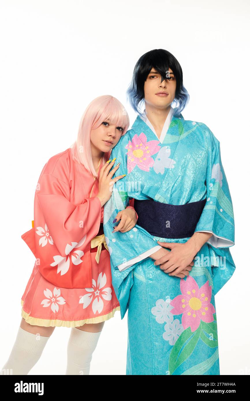 donna bionda in stile anime che si appoggia a un uomo stravagante in kimono colorato su personaggi cosplay bianchi Foto Stock