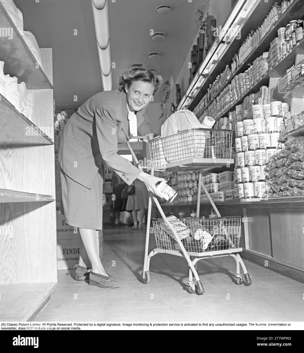 Shopping negli anni '1940 Una donna fa acquisti in un negozio self-service. Sia l'idea del self-service che il carrello della spesa provenivano dall'America e miravano ad aumentare le vendite. Il cliente potrebbe scegliere i generi alimentari e mettere il carrello della spesa e procedere al checkout del negozio. In questo periodo questo modo di shopping moderno era un nuovo introdotto in Svezia. 1949. Kristoffersson rif. AS47-1 Foto Stock