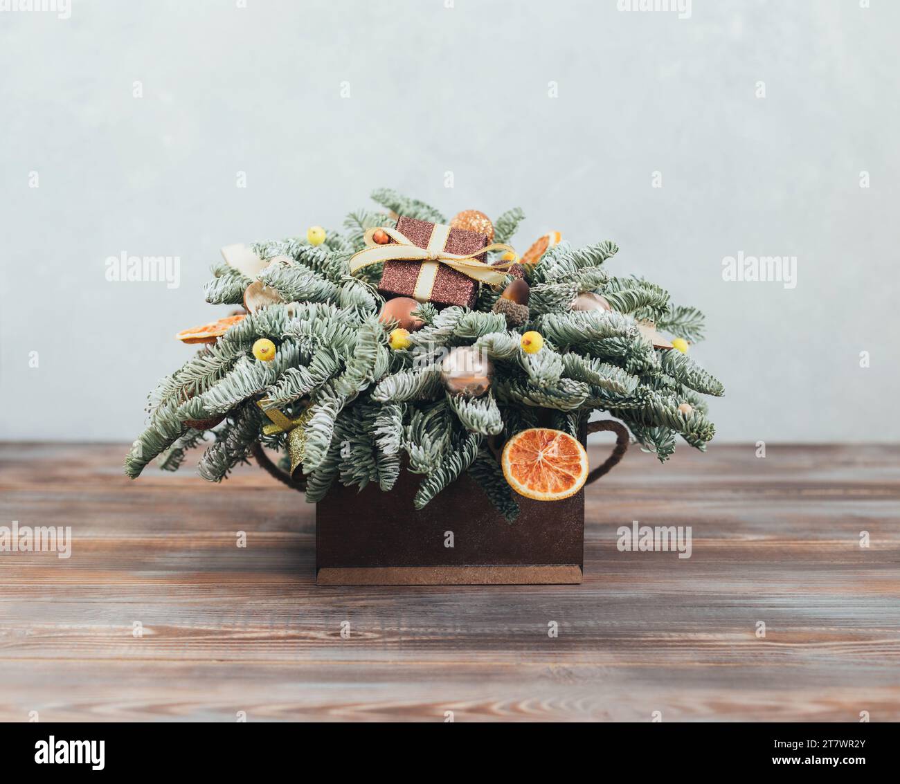 Bouquet di Natale. Composizione natalizia con rami di abete, baule e un regalo su sfondo di legno. Decorazioni per l'anno nuovo. Foto Stock
