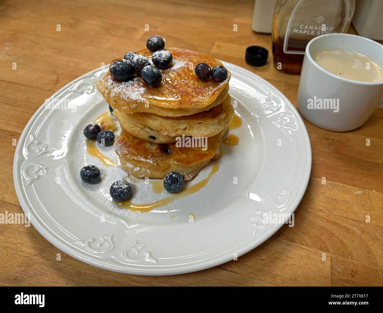 Una pila di pancake ai mirtilli appena fatti con sciroppo d'acero e caffè. Foto Stock