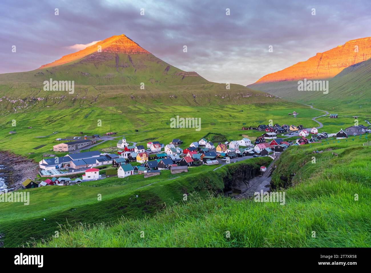 Case colorate del villaggio di Gjogv con i monti illuminati dal sole, vista dell'alba, isola di Eysturoy, isole Faroe, Danimarca, Europa Foto Stock