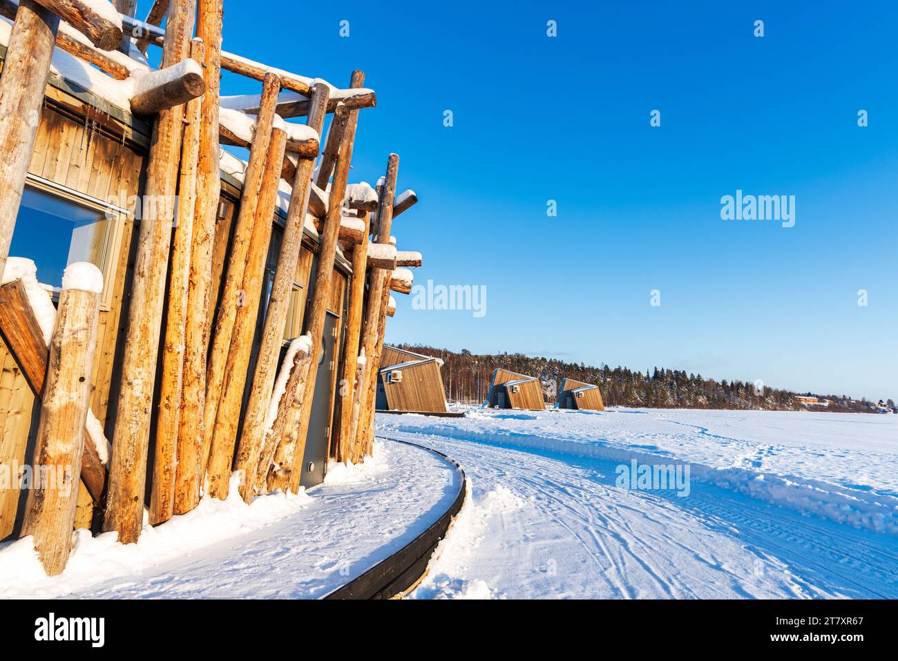Struttura architettonica dell'hotel Arctic Bath fatta di tronchi sul fiume Lule ghiacciato con chalet all'avanguardia sullo sfondo Foto Stock