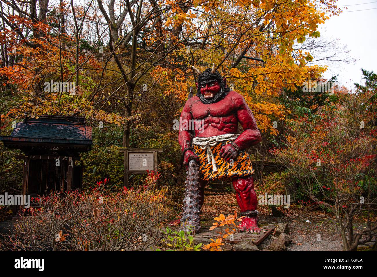 Statua di demone rosso in piedi con un grande club nella foresta autunnale, Noboribetsu, Hokkaido, Giappone, Asia Foto Stock