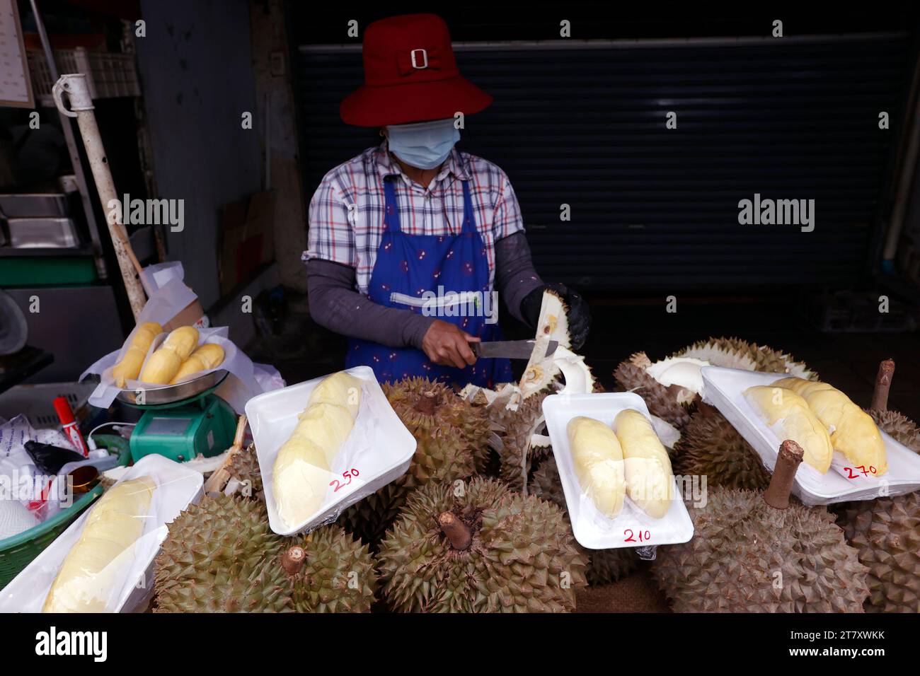 Una donna prepara la frutta Durian per la vendita in una bancarella di Street food popolare tra turisti e locali, Bangkok, Thailandia, Sud-est asiatico, Asia Foto Stock