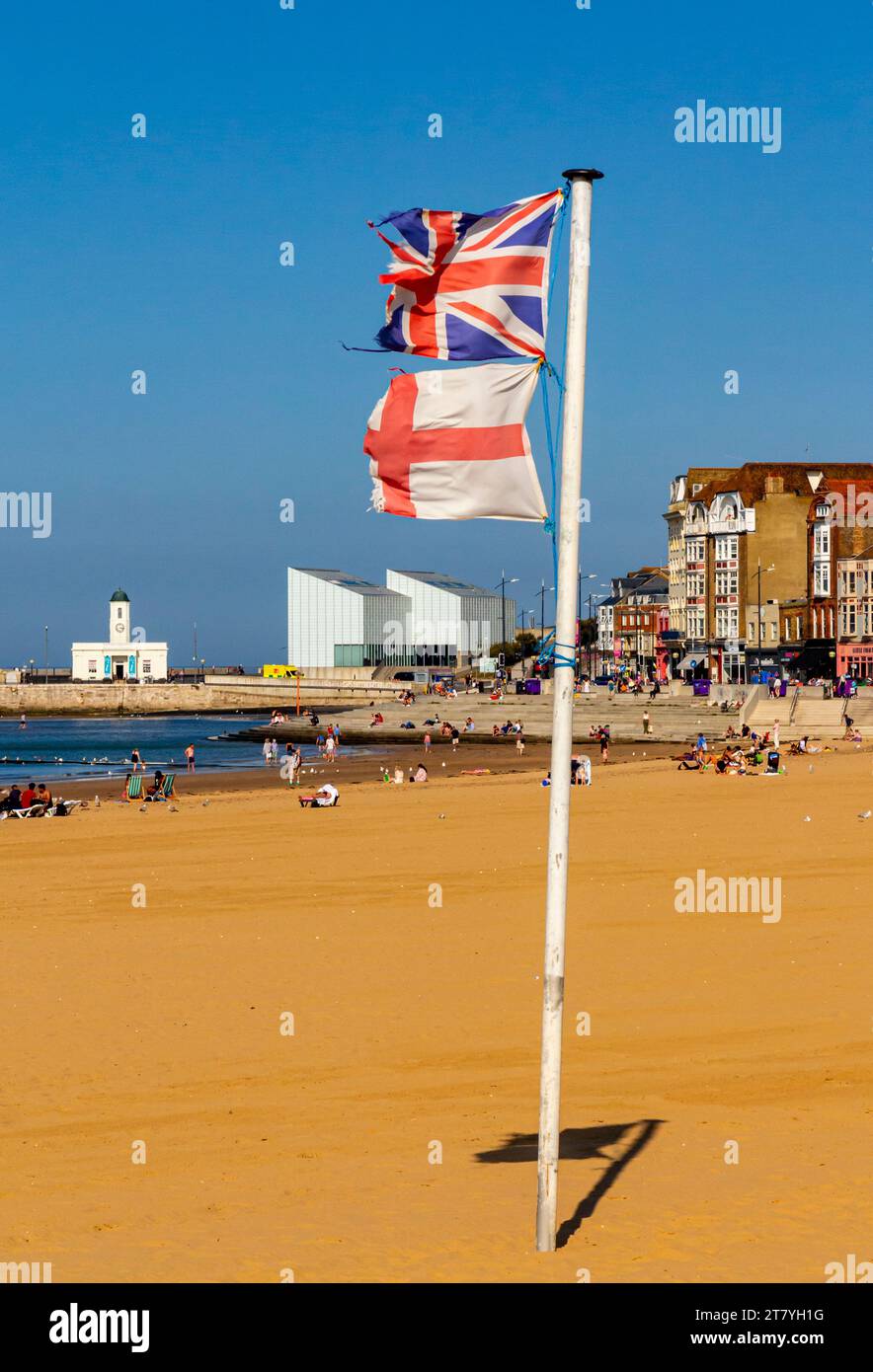 Spiaggia sabbiosa e passeggiata a Margate, località balneare sulla costa del Kent, nel sud-est dell'Inghilterra, con bandiere inglesi e inglesi schiacciate su un palo. Foto Stock