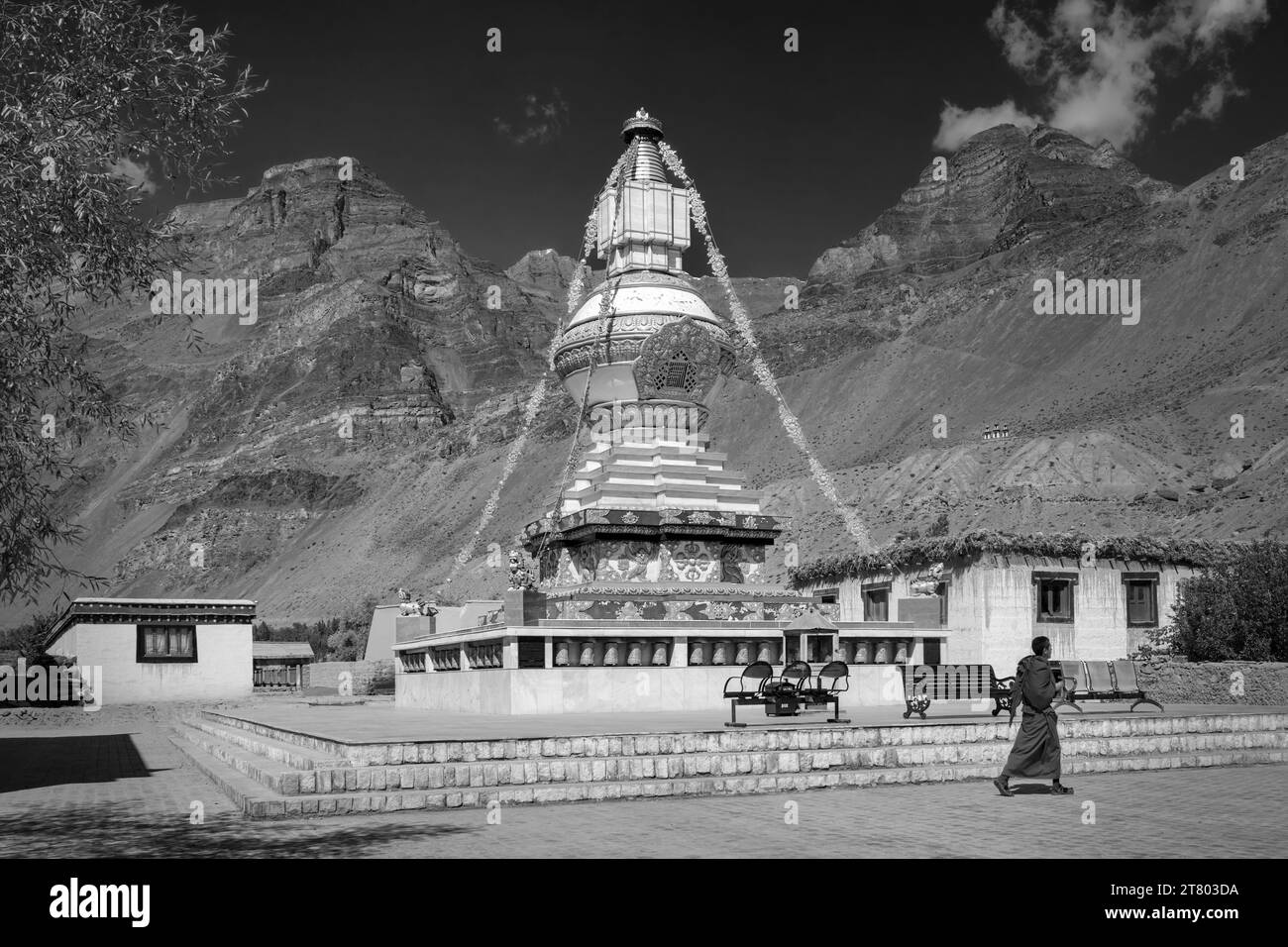 Grande stupa buddista con l'Himalaya come sfondo sotto il cielo luminoso con monaco non identificato che cammina davanti al villaggio di Tabo, Himachal Pradesh, India. Foto Stock
