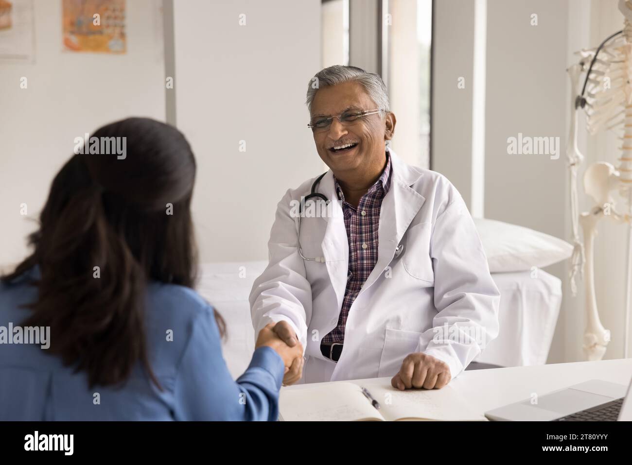 Allegro anziano medico indiano stringendo la mano con un paziente più giovane Foto Stock