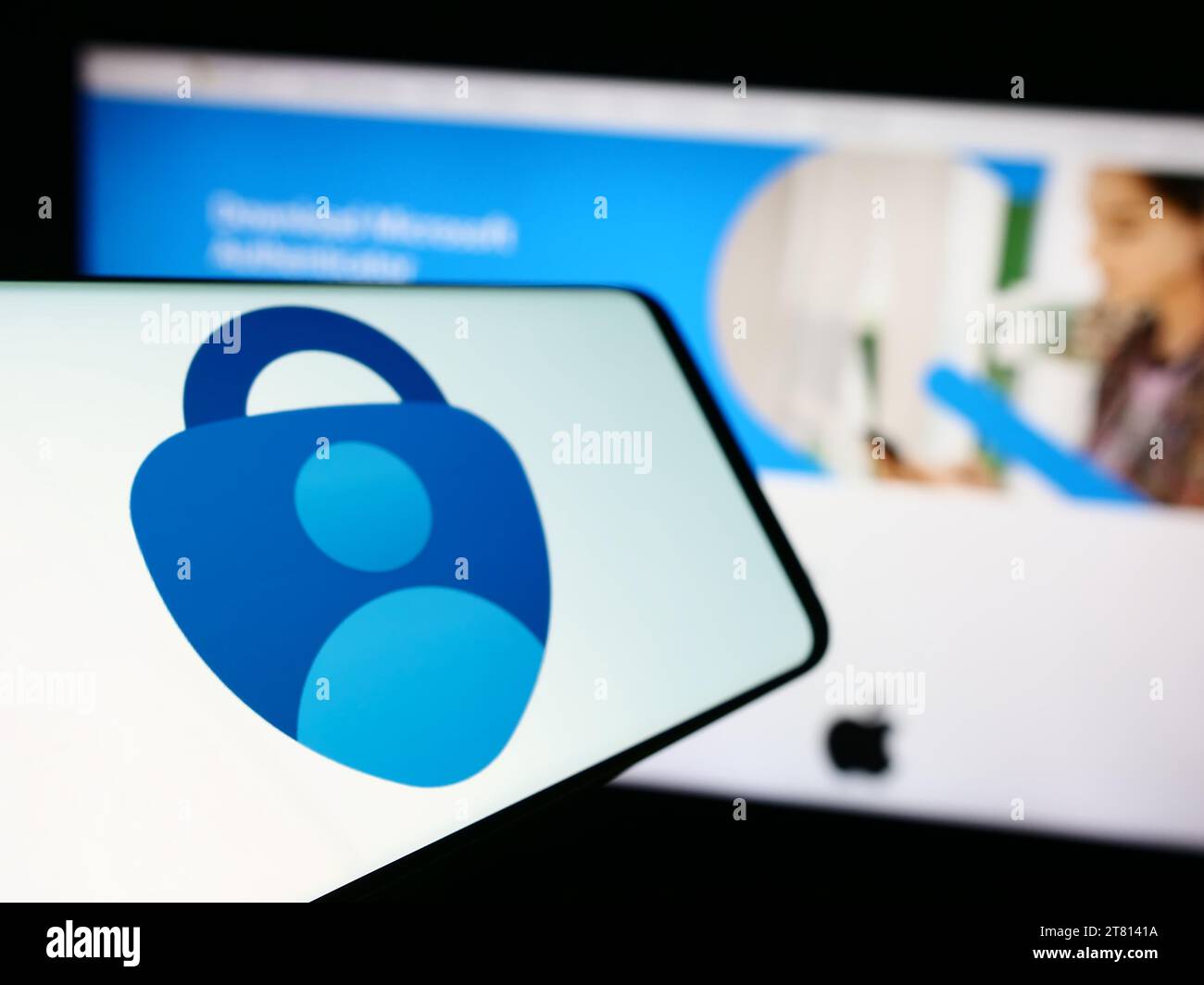 Smartphone con logo dell'app di autenticazione Microsoft Authenticator davanti al sito Web aziendale. Mettere a fuoco sul lato sinistro del display del telefono. Foto Stock