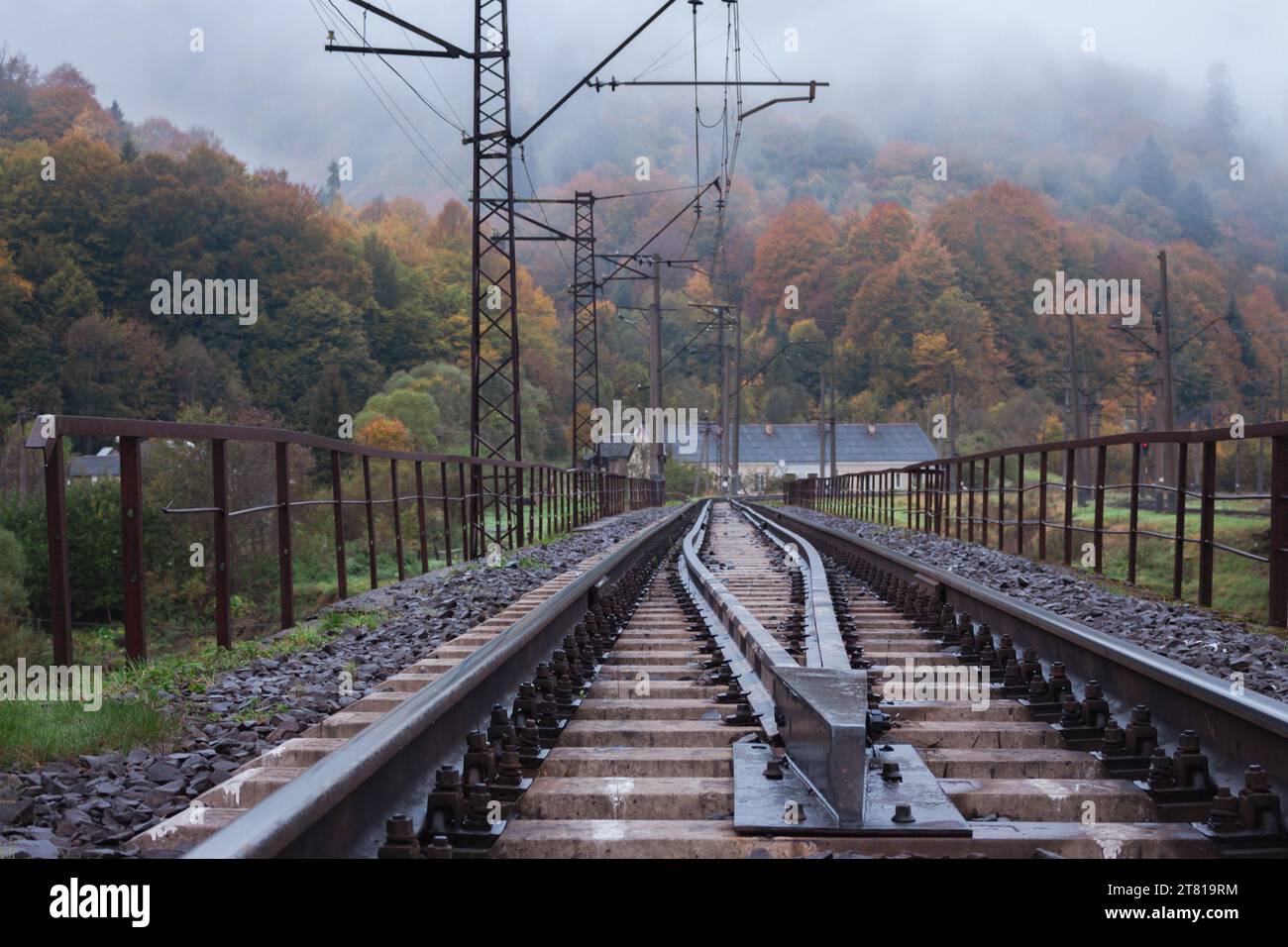 Ferrovia in montagna. Binari ferroviari nelle montagne autunnali. Ferrovia in un paesaggio mattutino nebbioso. Settore dei trasporti. Foto Stock